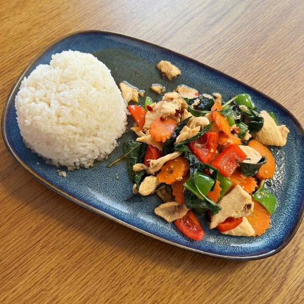 Chicken stir-fry with carrots, bell peppers, and basil, served with white rice on a blue plate.