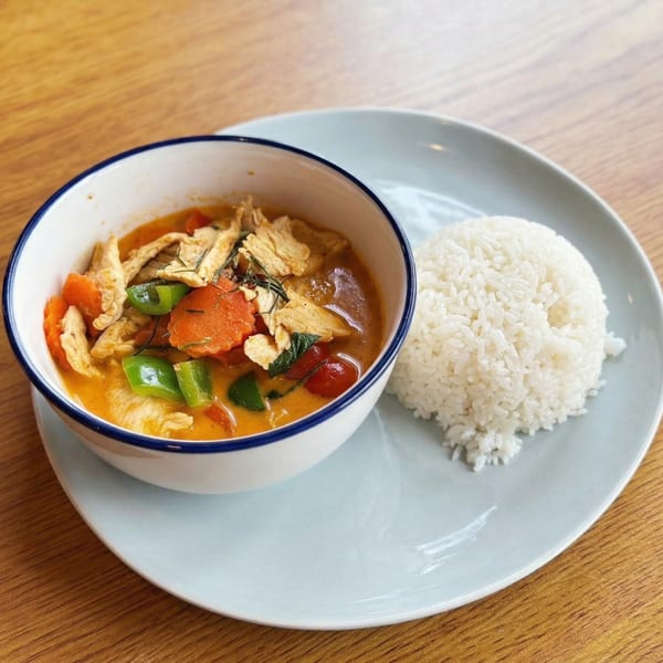 Red curry with chicken, carrots, and green peppers in a bowl, served with white rice.
