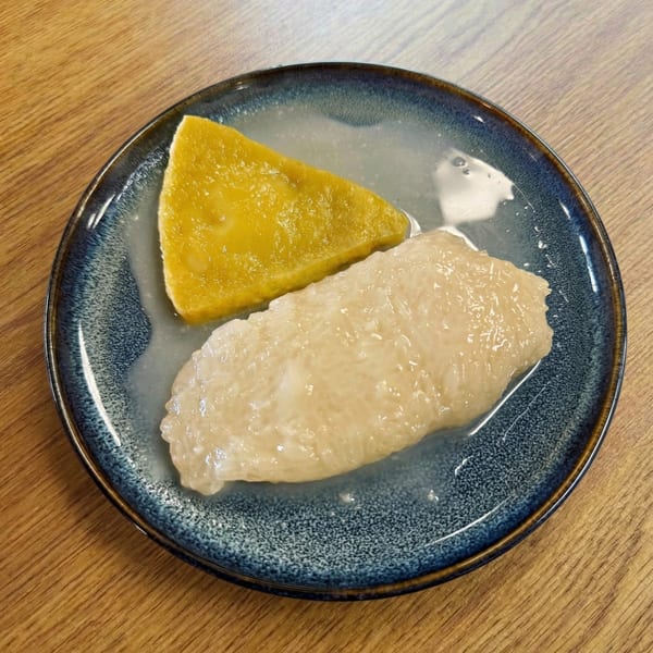 A blue plate holds a slice of yellow mango and a serving of sticky rice in coconut milk.