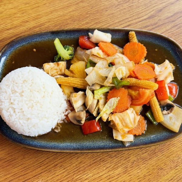 A colorful stir-fry with rice, featuring broccoli, carrots, baby corn, mushrooms, and bell peppers.
